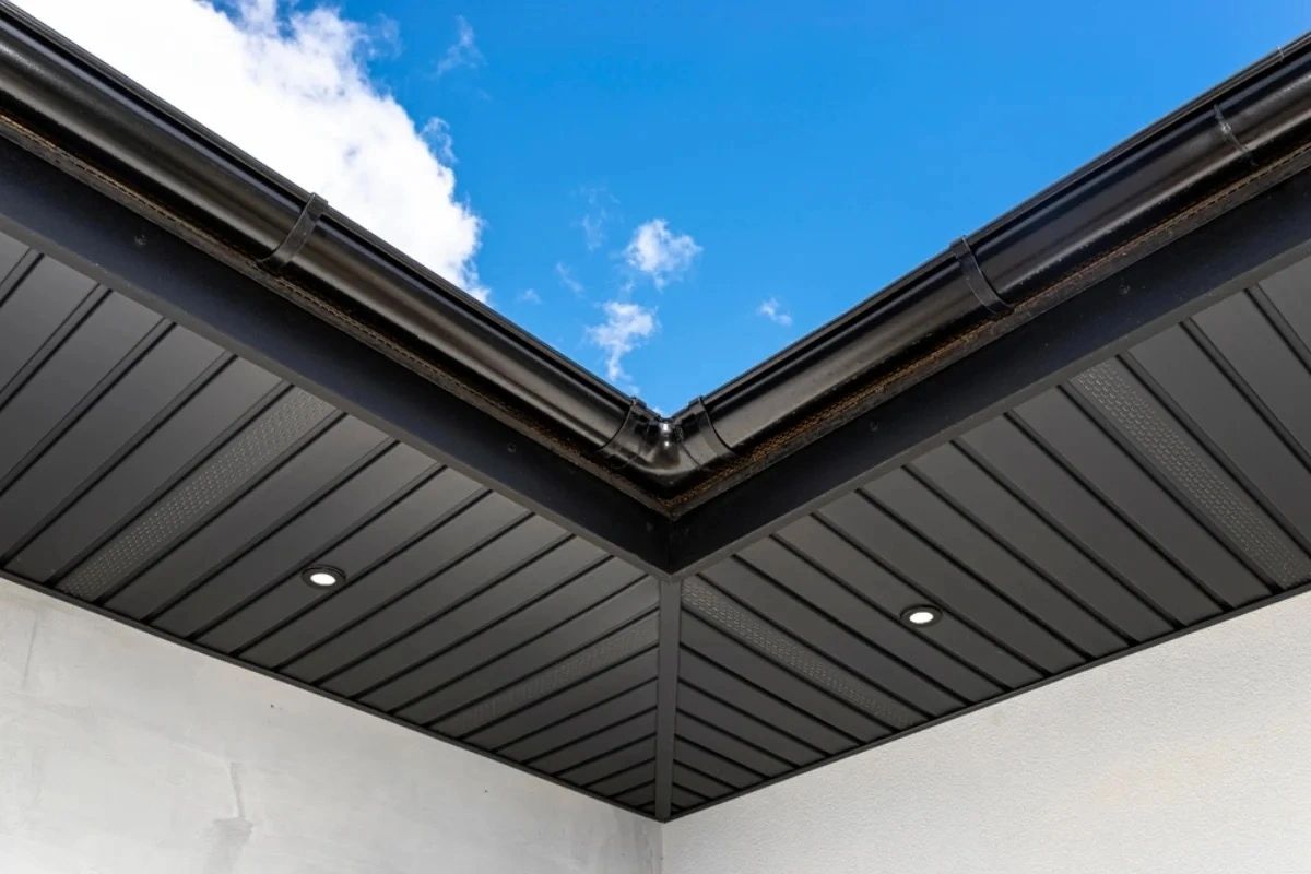 Modern building corner with black gutters and recessed lighting